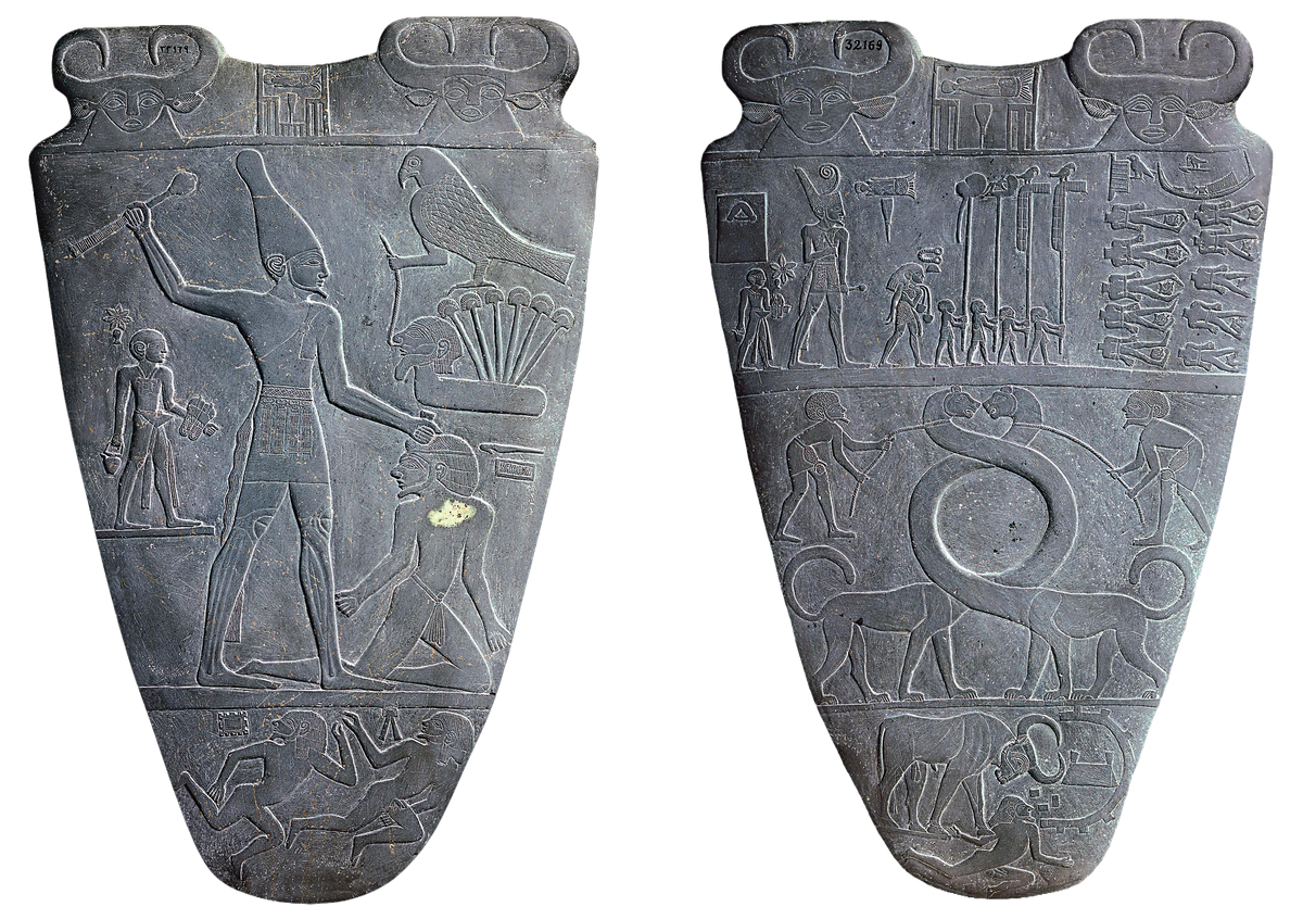 Two dark gray carved Egyptian steles shown side by side against a white background, each featuring relief carvings of figures, animals, and hieroglyphic symbols.